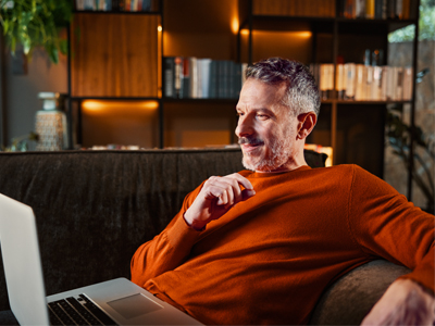Man sitting on a sofa working on a laptop – First Steps page illustration