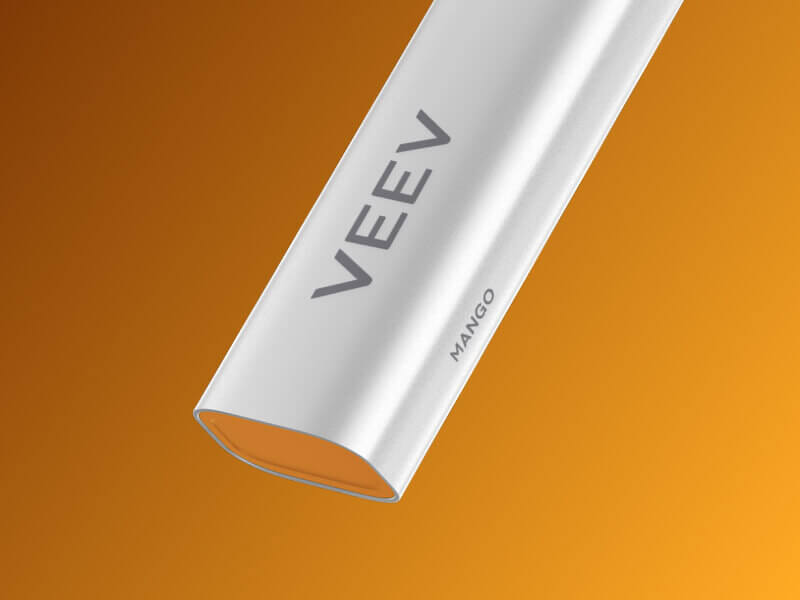 Close up of the bottom part of the VEEV NOW peach vape device on an orange patterned background