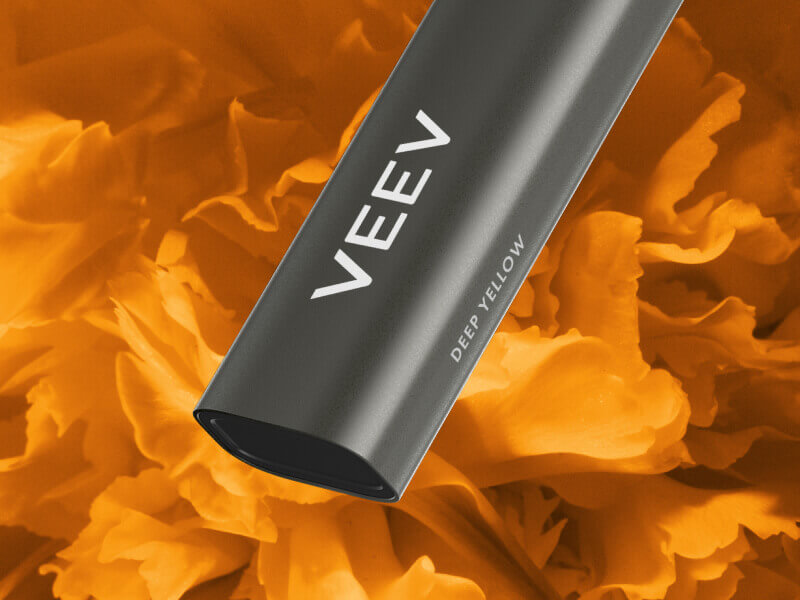 Close up of the bottom of the VEEV NOW vape device on an orange background