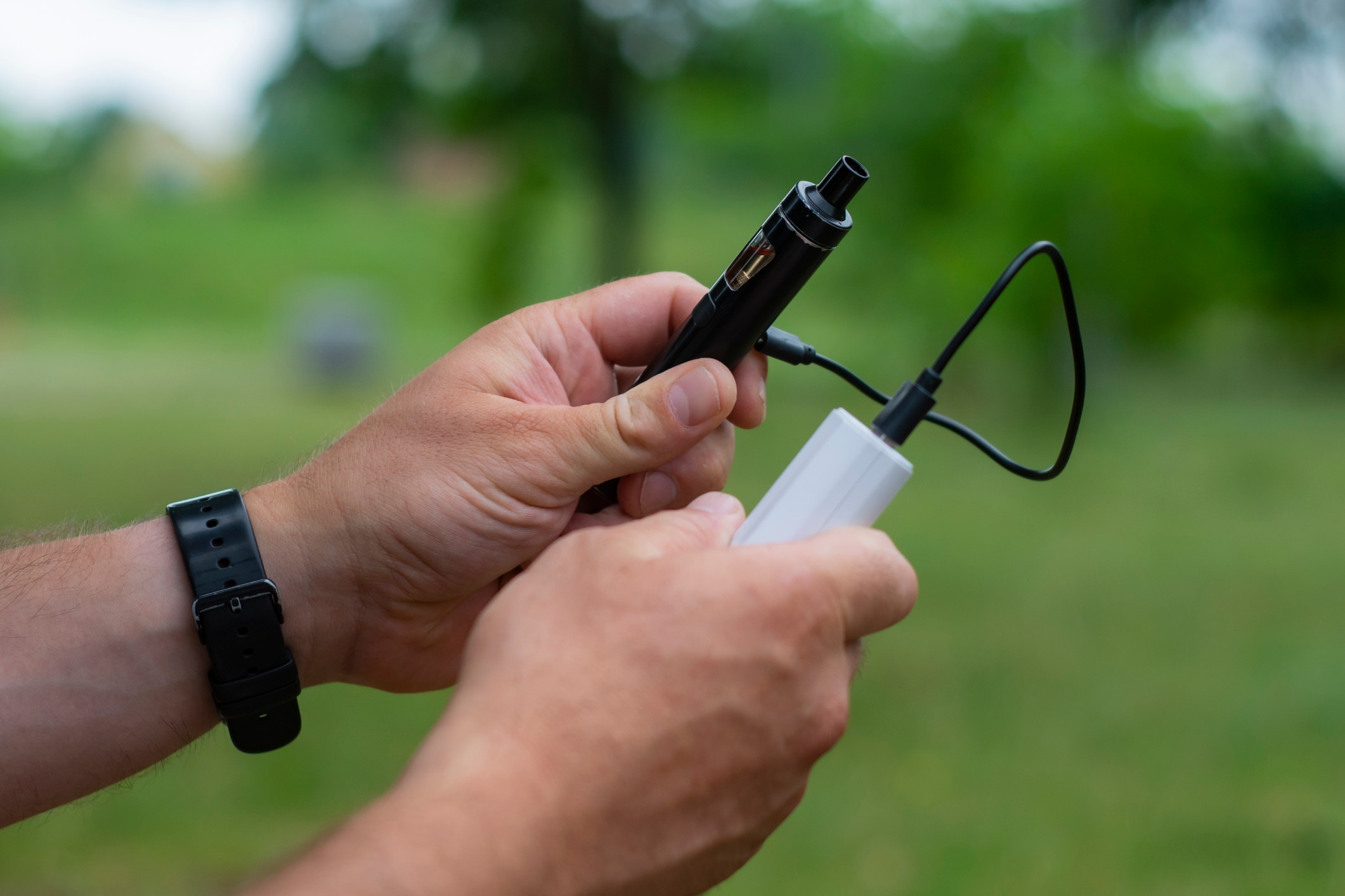 e-papieros z power bankiem trzymany w rekach