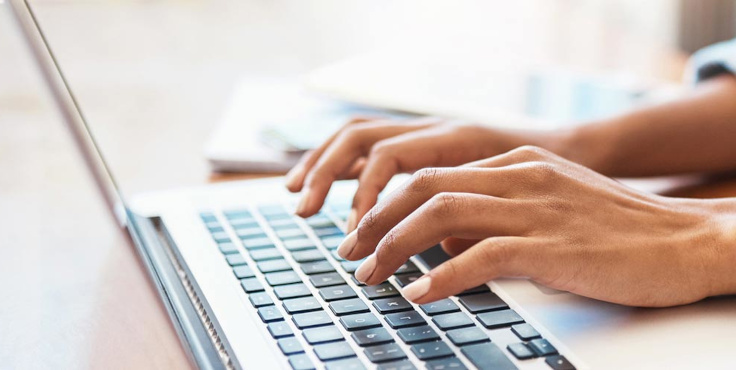 Zbliżenie na dłonie osoby piszącej na klawiaturze laptopa