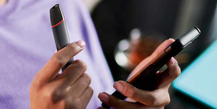 Zbliżenie na dłonie osoby trzymającej urządzenie VEEV w jednej ręce i telefon w drugiej